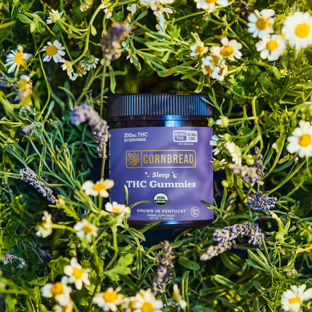 Cornbread THC Gummies container surrounded by greenery and flowers